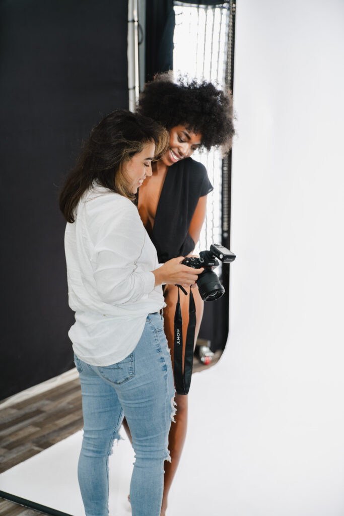 A woman photographer and female model smiling while reviewing images taken with camera in a studio in Boynton Beach, Florida.